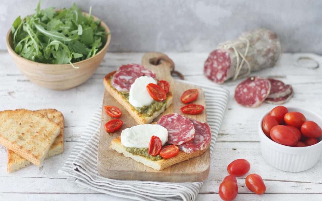 Bruschetta al pesto di rucola con mozzarella di bufala, pomodorini confit e Salame Felino IGP